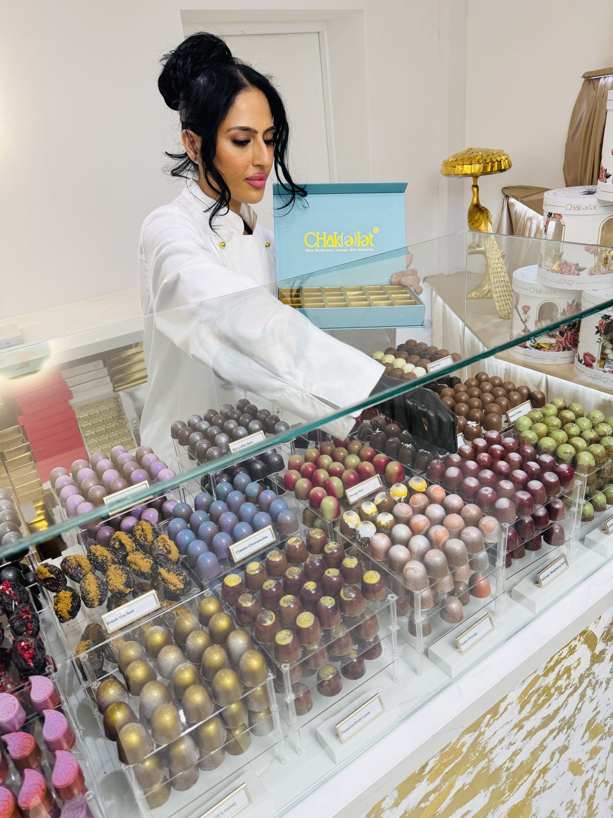 A business owner arranging handmade chocolates in the display counter of her Leeds Road shop.