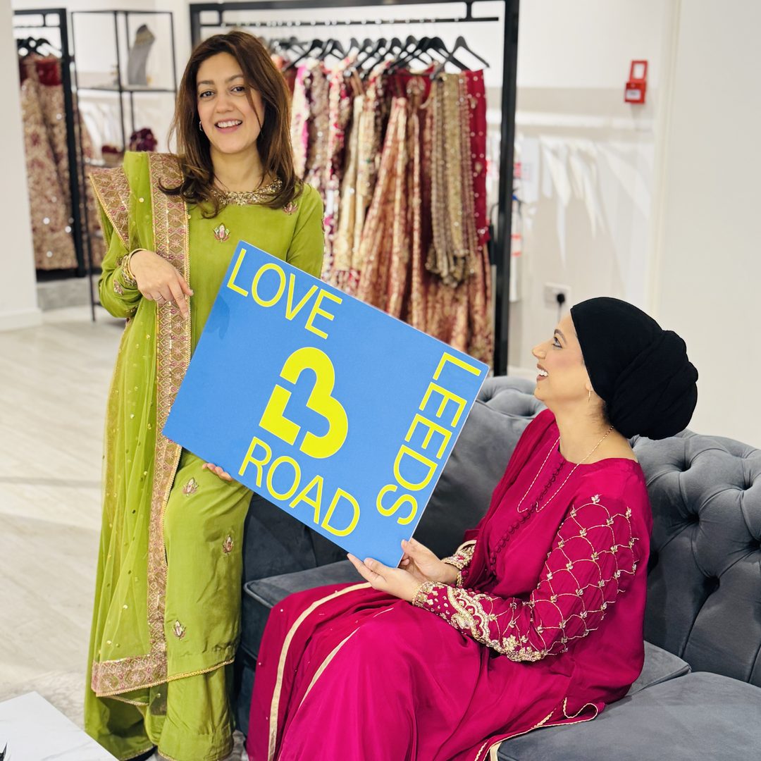 Two women in a Leeds Road boutique holding the Love Leeds Road sign.