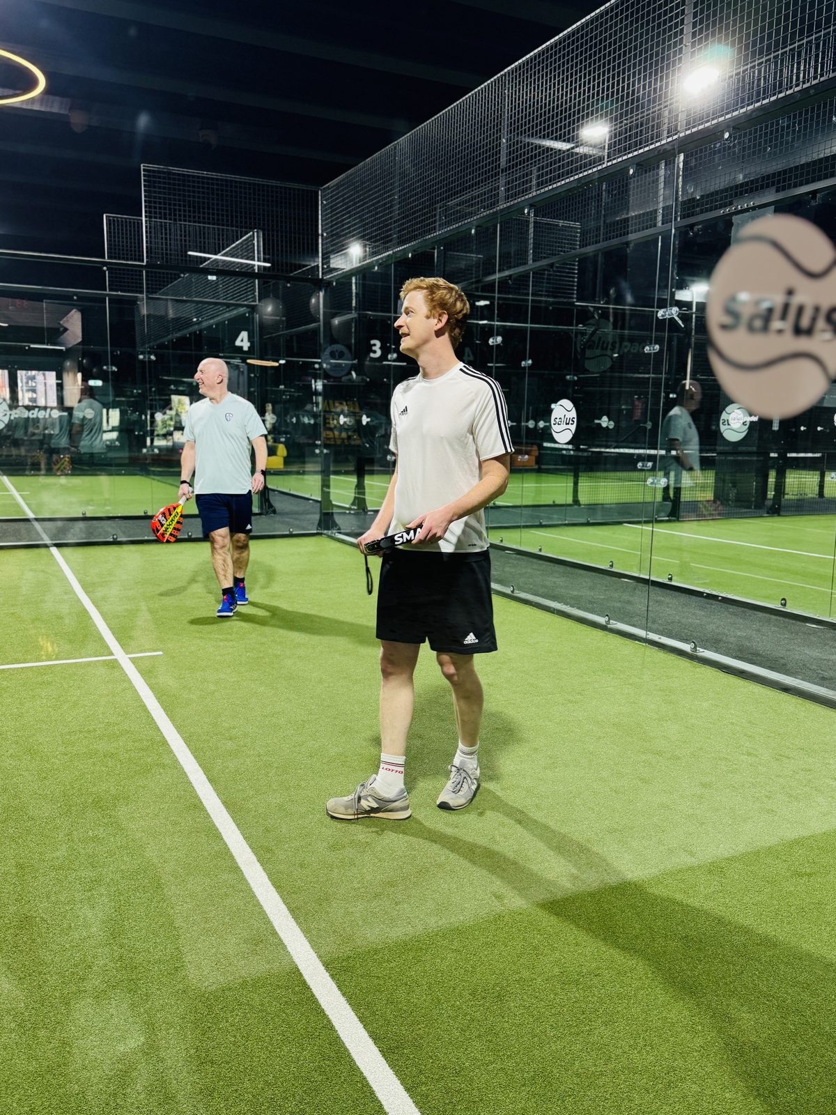 Players on the glass-walled padel courts at Salus Padel.