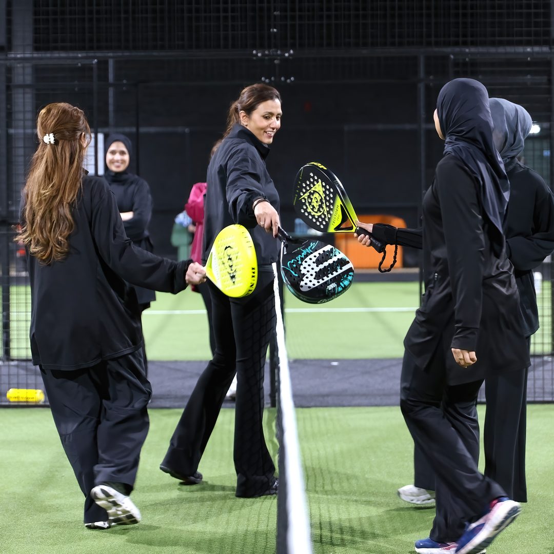 Players touching paddles across the net at the end of a session at Salus Padel.
