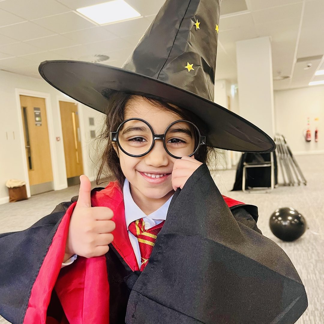 A child in a wizard hat and round glasses giving a thumbs up at a Making Sparks event.